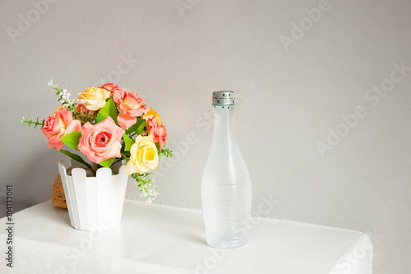 Fototapeta flower and bottle of water, on white table