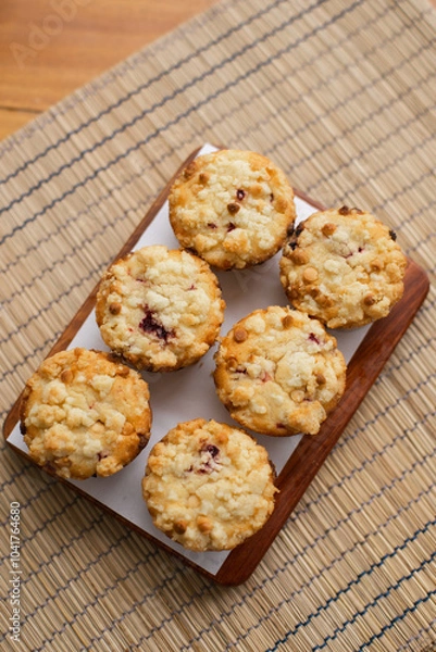 Fototapeta muffins arranged on a wooden board with a white paper underneath.