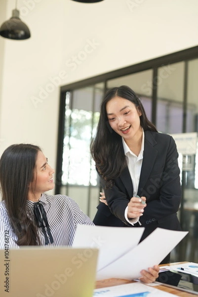 Obraz  Group of happy Asian business people having a meeting at the office. Two women working together using modern laptops.