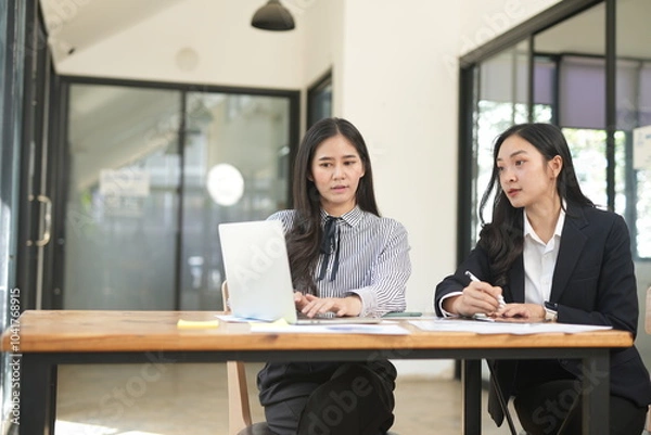 Obraz Two businesswomen are considering documents in an office.