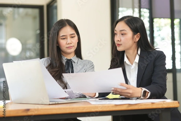 Obraz Group of happy Asian business people having a meeting at the office. Two women working together using modern laptops.