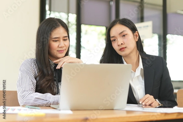 Obraz Two businesswomen are considering documents in an office.