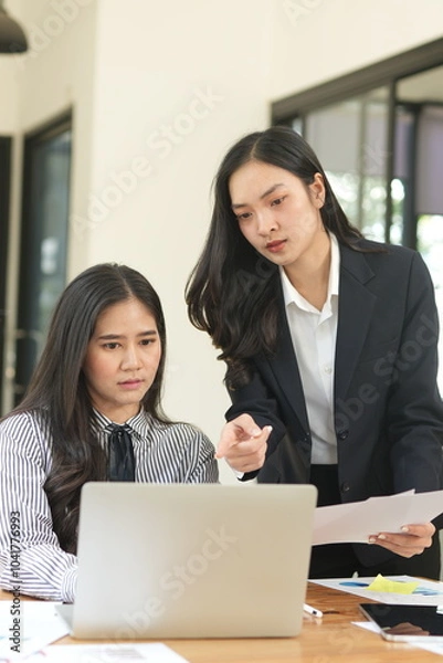 Obraz Group of happy Asian business people having a meeting at the office. Two women working together using modern laptops.