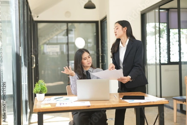 Obraz Two businesswomen are considering documents in an office.