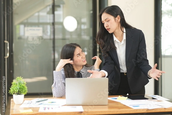 Obraz Two businesswomen are considering documents in an office.