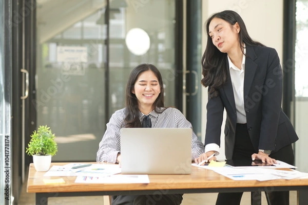 Obraz  Group of happy Asian business people having a meeting at the office. Two women working together using modern laptops.