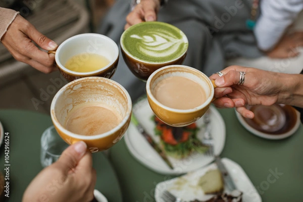 Fototapeta Four friends gather for breakfast and toasting with cups of coffee, buckwheat tea and matcha latte on the summer terrace.