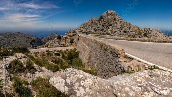 Fototapeta Mountain road MA-2141 at Nus de sa Corbata, where the road crosses itself in a twisting tie-knot formation, offering views of the Serra de Tramuntana mountains and Mediterranean Sea, ideal for cycling