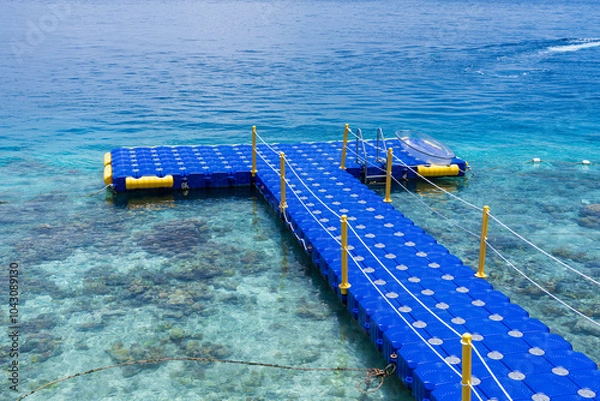 Fototapeta Modular Plastic Floating Pontoon made from blue plastic cubes, with clear see-through transparent sea kayak