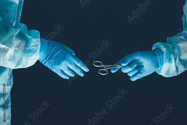 Fototapeta Two surgeons working and passing surgical equipment in the operating room