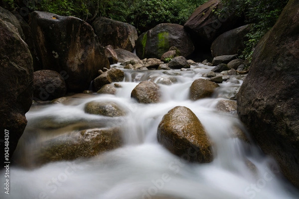 Fototapeta A stunning waterfall hidden deep in a lush, green forest. , surrounded by towering trees and rich foliage, creating a serene and mystical atmosphere