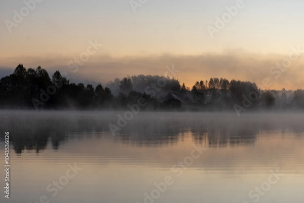 Fototapeta Blurred landscape with a lake in the morning fog, fog trailing over the lake