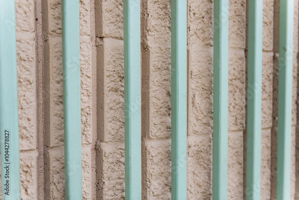 Fototapeta Turqoise metal bars in front of stone wall