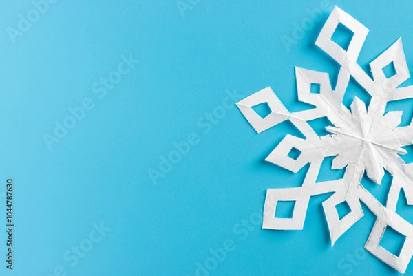 Obraz white paper cut out snowflakes in light blue background. Empty space for copy space. winter or christmas theme background. selective focus.