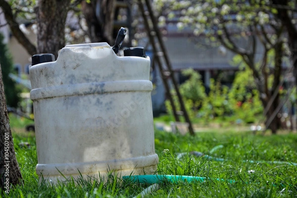 Obraz Water tank for watering the grass. Container to retain rainwater in the garden. White plastic jerrycan. Gallon water reserve