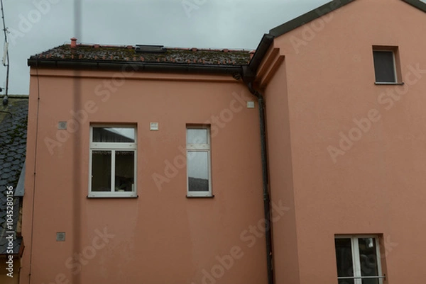 Fototapeta There is a pinkcolored building adorned with two windows and featuring a charming chimney situated prominently on the roof