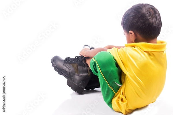 Fototapeta little boy try wearing big shoe,focus shoe