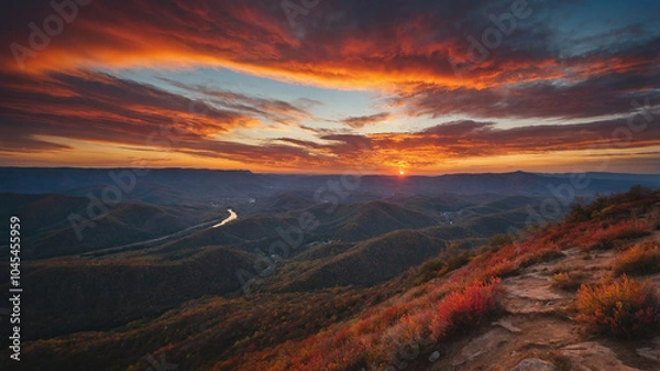 Fototapeta Breathtaking sunset over rolling hills with vibrant autumn colors reflected in a winding river below.