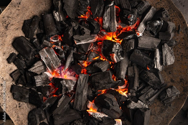 Obraz Hot coals with vibrant red and orange hues, emitting intense heat. Glowing pieces surrounded by dark ash, creating a rustic atmosphere