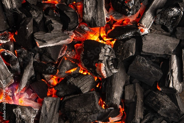 Obraz Hot coals with vibrant red and orange hues, emitting intense heat. Glowing pieces surrounded by dark ash, creating a rustic atmosphere