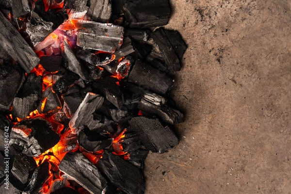 Obraz Hot coals with vibrant red and orange hues, emitting intense heat. Glowing pieces surrounded by dark ash, creating a rustic atmosphere