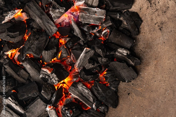 Obraz Hot coals with vibrant red and orange hues, emitting intense heat. Glowing pieces surrounded by dark ash, creating a rustic atmosphere