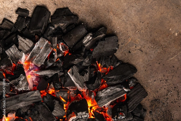 Obraz Hot coals with vibrant red and orange hues, emitting intense heat. Glowing pieces surrounded by dark ash, creating a rustic atmosphere