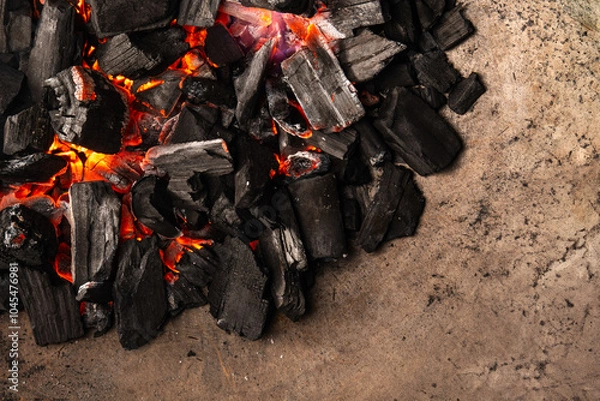 Obraz Hot coals with vibrant red and orange hues, emitting intense heat. Glowing pieces surrounded by dark ash, creating a rustic atmosphere