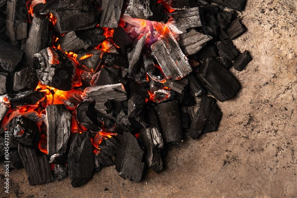 Obraz Hot coals with vibrant red and orange hues, emitting intense heat. Glowing pieces surrounded by dark ash, creating a rustic atmosphere