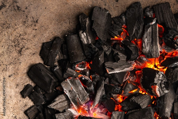 Obraz Hot coals with vibrant red and orange hues, emitting intense heat. Glowing pieces surrounded by dark ash, creating a rustic atmosphere