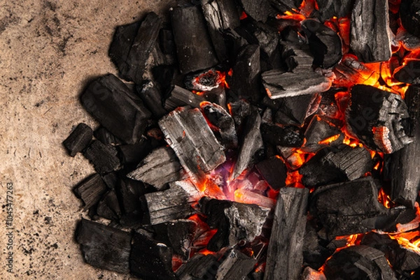 Obraz Hot coals with vibrant red and orange hues, emitting intense heat. Glowing pieces surrounded by dark ash, creating a rustic atmosphere