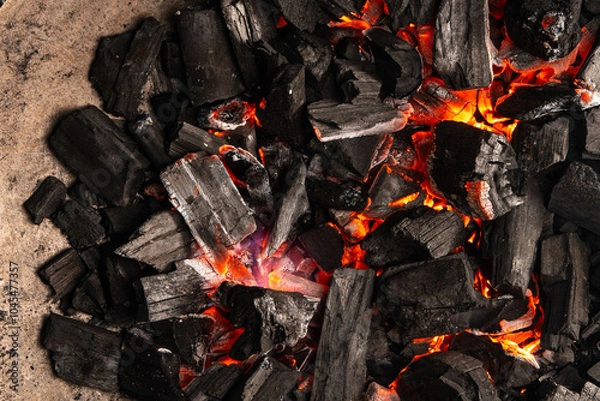 Obraz Hot coals with vibrant red and orange hues, emitting intense heat. Glowing pieces surrounded by dark ash, creating a rustic atmosphere