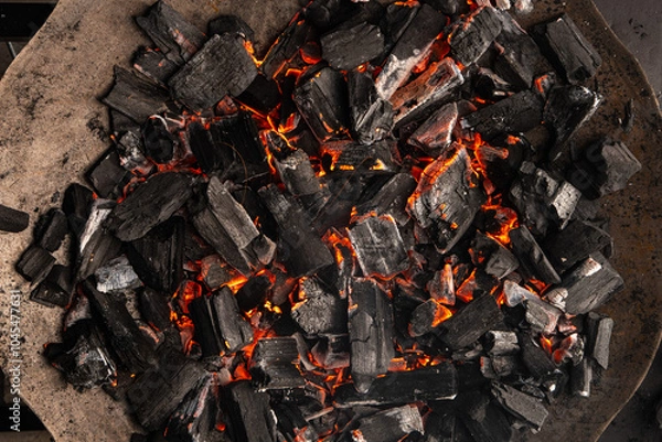 Obraz Hot coals with vibrant red and orange hues, emitting intense heat. Glowing pieces surrounded by dark ash, creating a rustic atmosphere