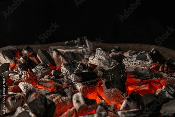 Obraz Hot coals with vibrant red and orange hues, emitting intense heat. Glowing pieces surrounded by dark ash, creating a rustic atmosphere