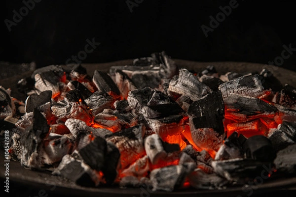 Obraz Hot coals with vibrant red and orange hues, emitting intense heat. Glowing pieces surrounded by dark ash, creating a rustic atmosphere