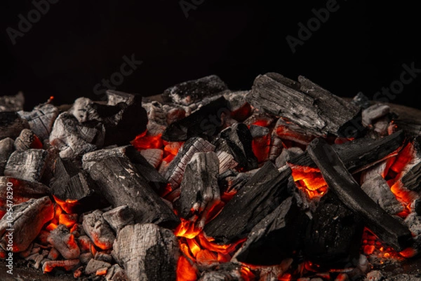 Obraz Hot coals with vibrant red and orange hues, emitting intense heat. Glowing pieces surrounded by dark ash, creating a rustic atmosphere