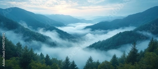 Fototapeta Serene mountain landscape with mist and trees at dawn.