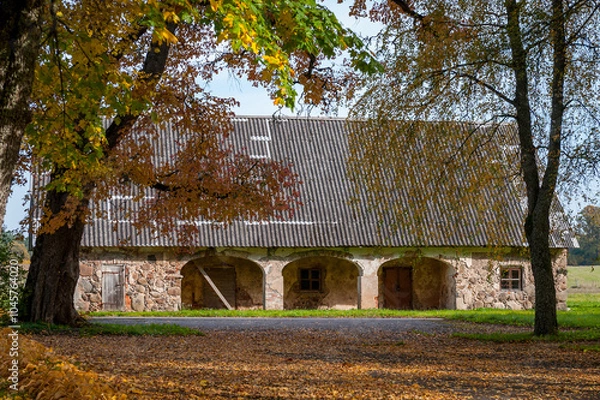Obraz Rural autumn landscape with stone shed and asbestos roof. Igate Manor, Latvia.
