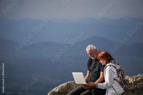 Obraz Elderly couple using a laptop on top of a mountain