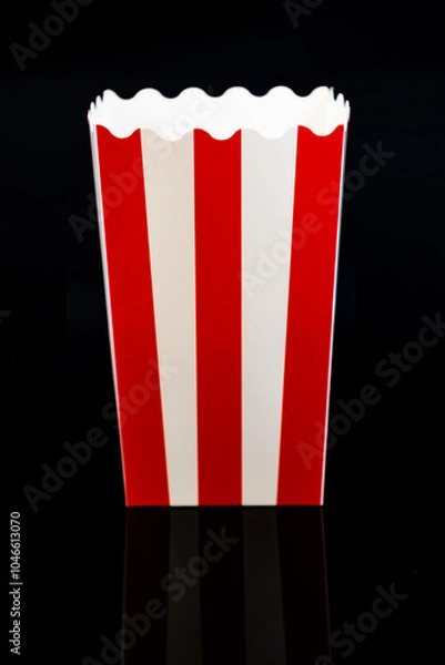 Fototapeta Vertical image of cardboard popcorn bucket reflected on a black background, cinema and popcorn concept