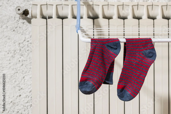 Fototapeta Colorful socks hanging on the clothesline drying on the radiator at home in winter.