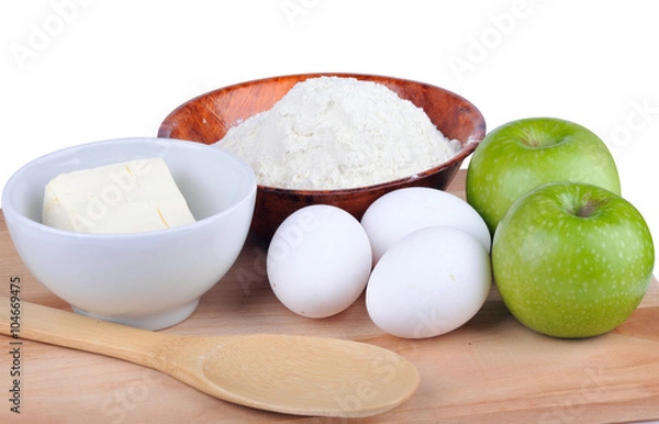 Fototapeta Butter, flour, eggs and apples on a wooden board