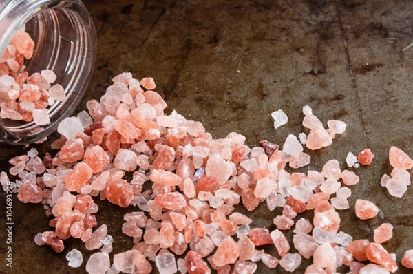 Obraz Scattered Himalayan pink salt crystals from glass bottle on rusty metal background