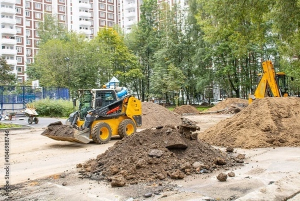 Fototapeta A bulldozer is actively loading soil into a sizable pile on a construction site