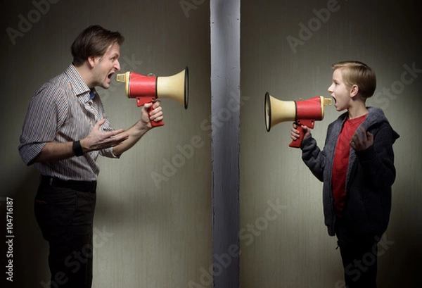 Fototapeta Tween son and his father yelling through the megaphones standing on either side of a wall