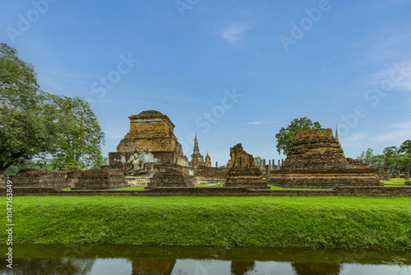 Fototapeta Ancient Buddha statue and ruin of temple of Wat mahathat temple in Sukhothai Historical Park, which also one of UNESCO Heritage Site