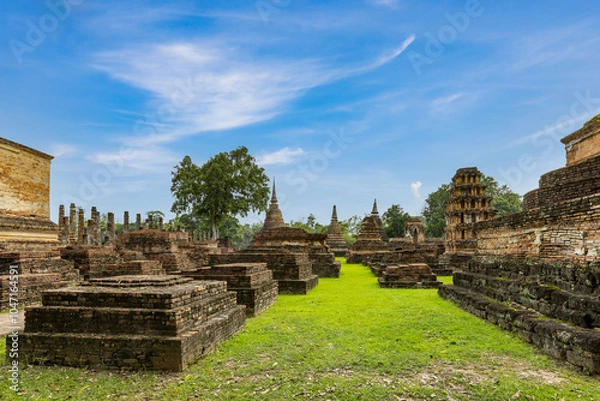 Fototapeta Ancient Buddha statue and ruin of temple of Wat mahathat temple in Sukhothai Historical Park, which also one of UNESCO Heritage Site