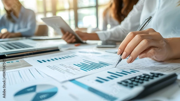 Obraz Professional team analyzing financial statements in a bright, modern workspace.  -