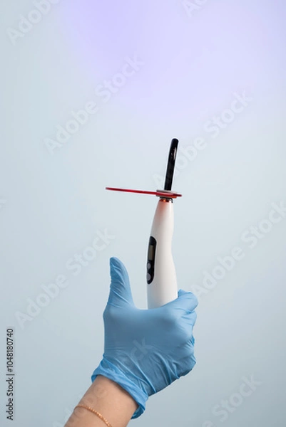 Fototapeta Dental assistant holding a curing light for dental procedures in a modern clinic during an appointment