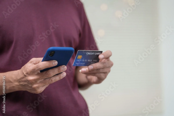 Fototapeta Close-up of a man's hand holding a bank credit card, highlighting online services for lending and access to credit,demonstrating financial convenience and flexibility for secure digital transactions